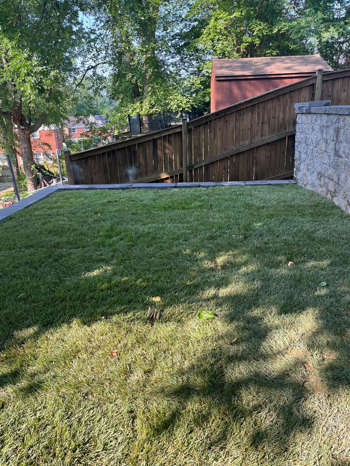 Lawn with wood fence and stone retaining wall