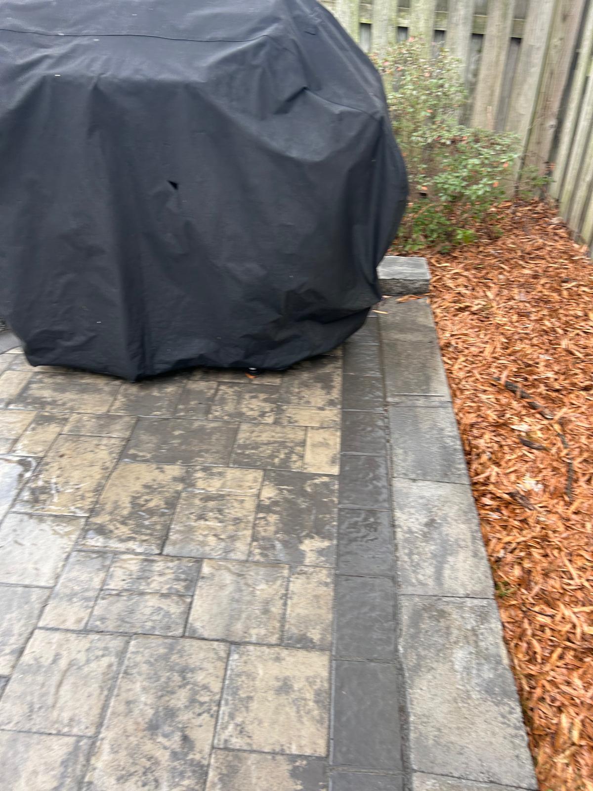 Mulched bed full of fall leaves along a finished paver patio by Kaeler